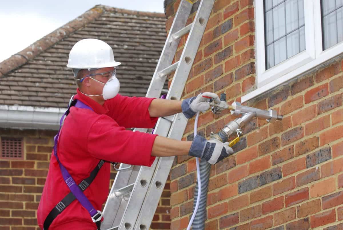 Worker injecting foam into home's walls.