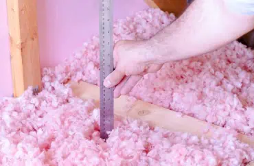 A man measuring the amount of insulation in a Michigan home.