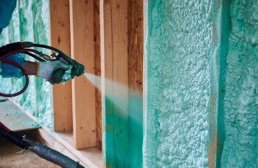 A man in Michigan spraying foam insulation on a home wall.