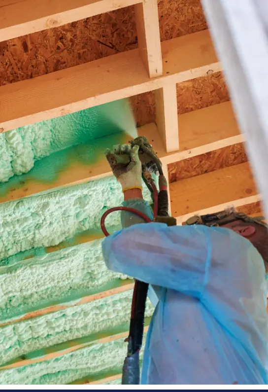 A man is spraying foam insulation on a wooden ceiling in Michigan for home improvement.
