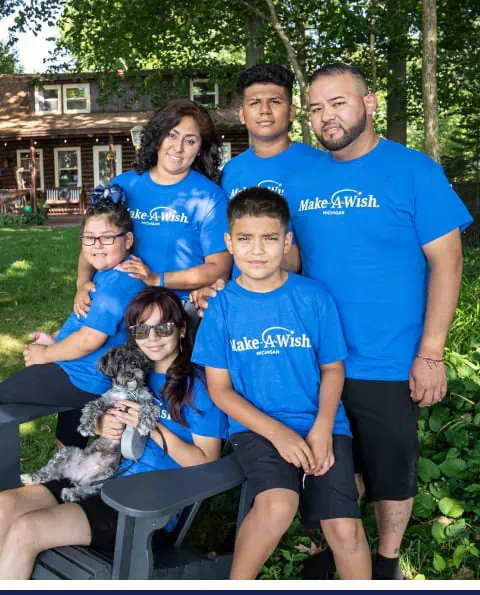 A family posing for a photo in blue t-shirts at home.