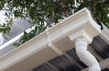 A white gutter with a pipe attached to it for exterior remodeling.