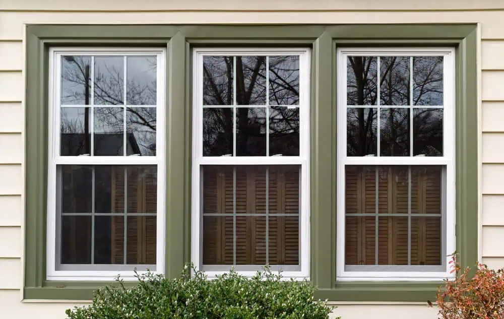 A bank of three vinyl double-hung windows with green trim