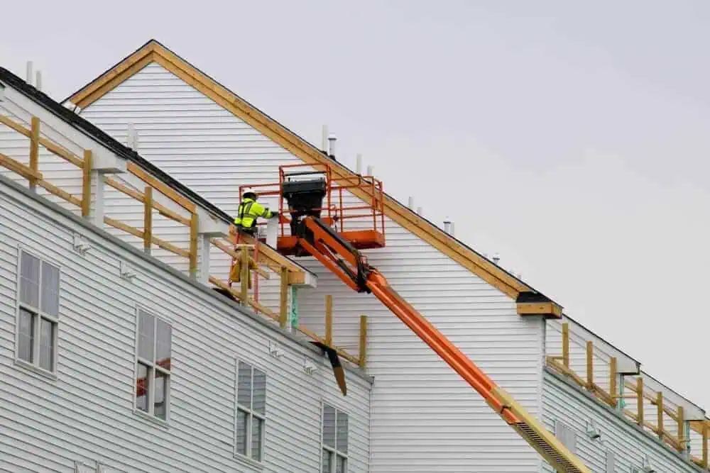 Exterior remodeling contractor on a lift working on the roof flashing of a residential home