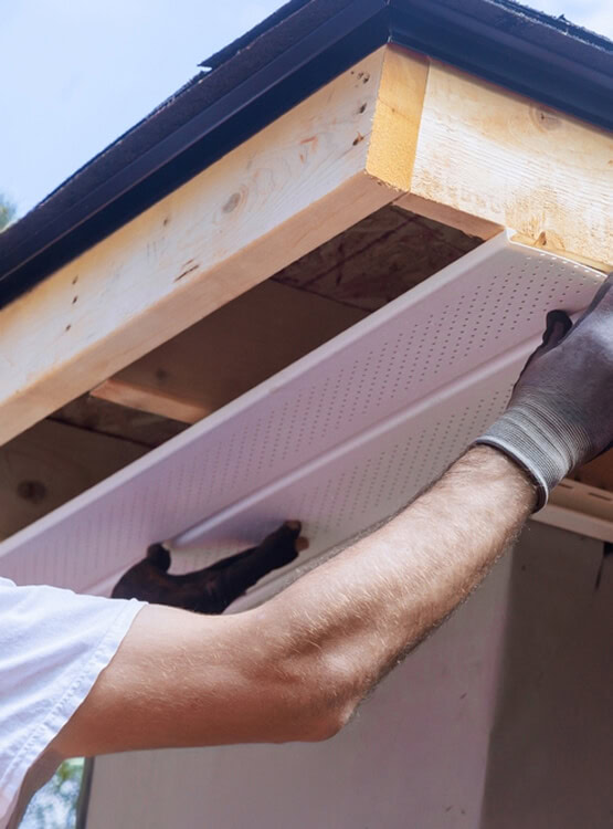 A Michigan roofing services expert installs a soffit panel, prepping for gutter and siding work.