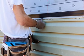 A worker installs vinyl siding on a Michigan home, showing roofing, gutter, and window services.