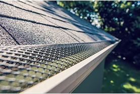 Close-up of Michigan roof repair with asphalt shingles, gutter services, and metal mesh.