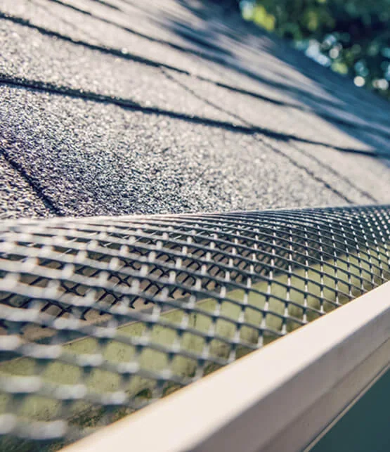 Close-up of Michigan roof repair with gray shingles and gutter services mesh guard installed.
