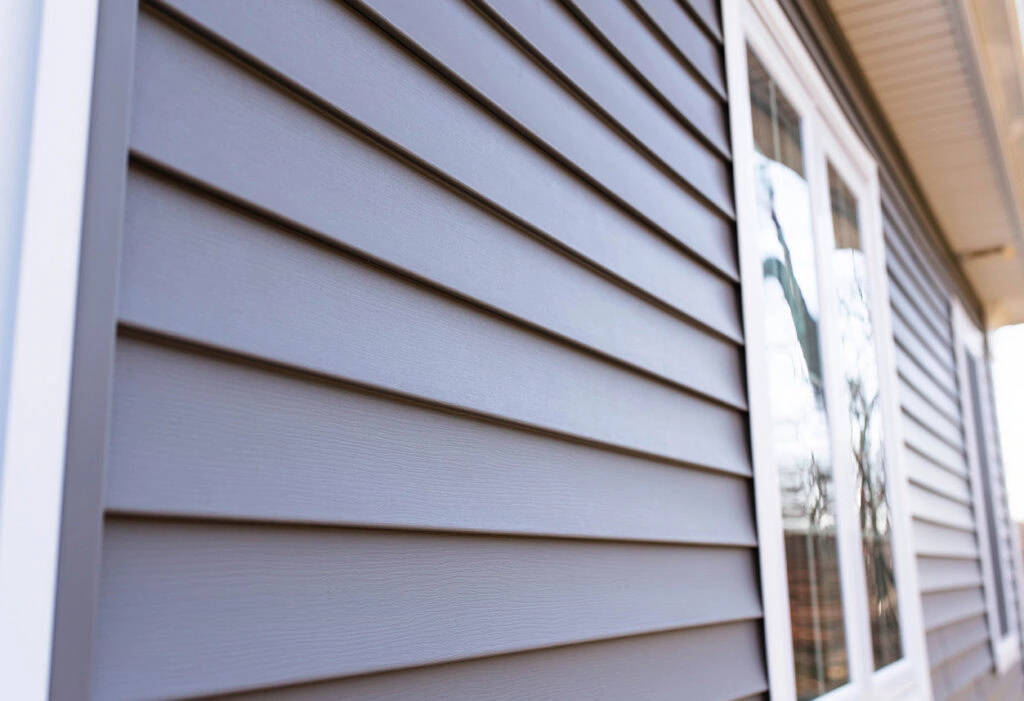 Gray insulated vinyl siding installed around residential windows and exterior walls